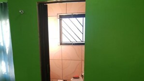 A bathroom with green walls, a toilet, a sink, and a window with bars. - Luc Lodge (Cape Town)