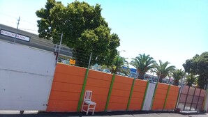 A parking lot with a large orange and white fence, a white chair, and a sign for 'Halal Fish and Chips'. - Luc Lodge (Cape Town)