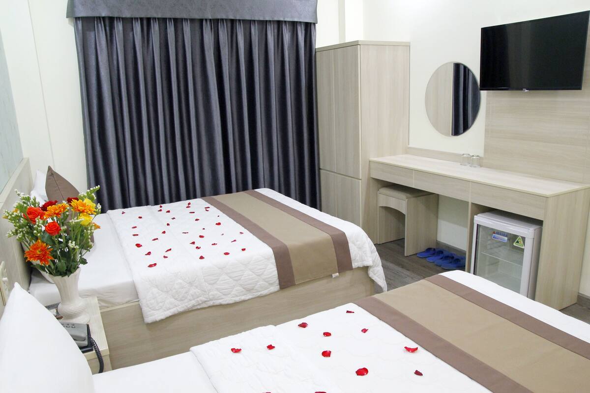 Een hotelkamer met twee bedden, een bureau, een spiegel, een televisie en een minibar.