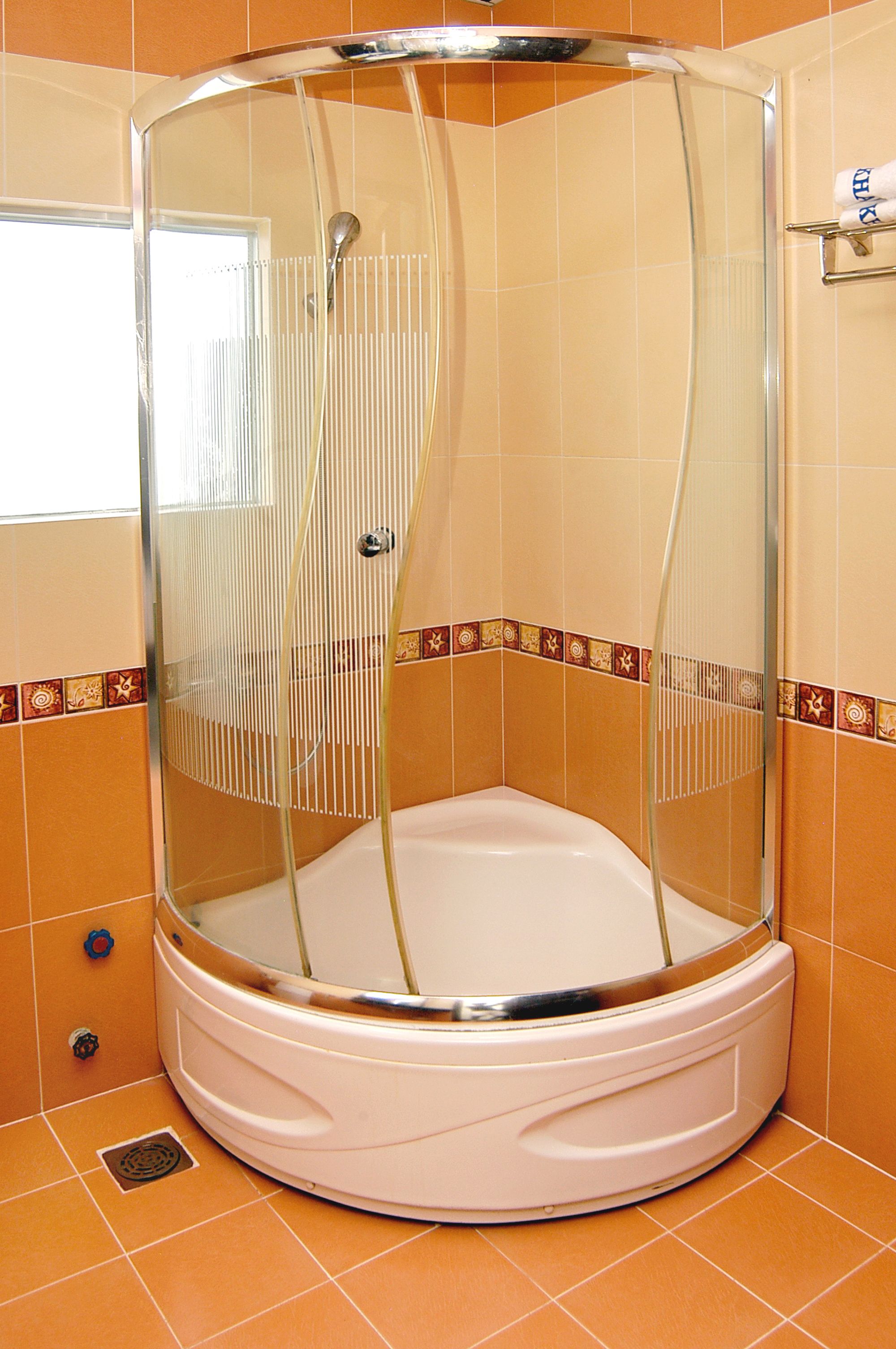 A shower enclosure with a glass door and a white base.