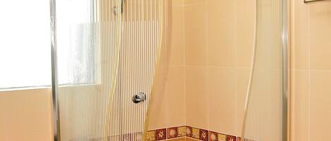 A shower enclosure with a glass door and a white base.