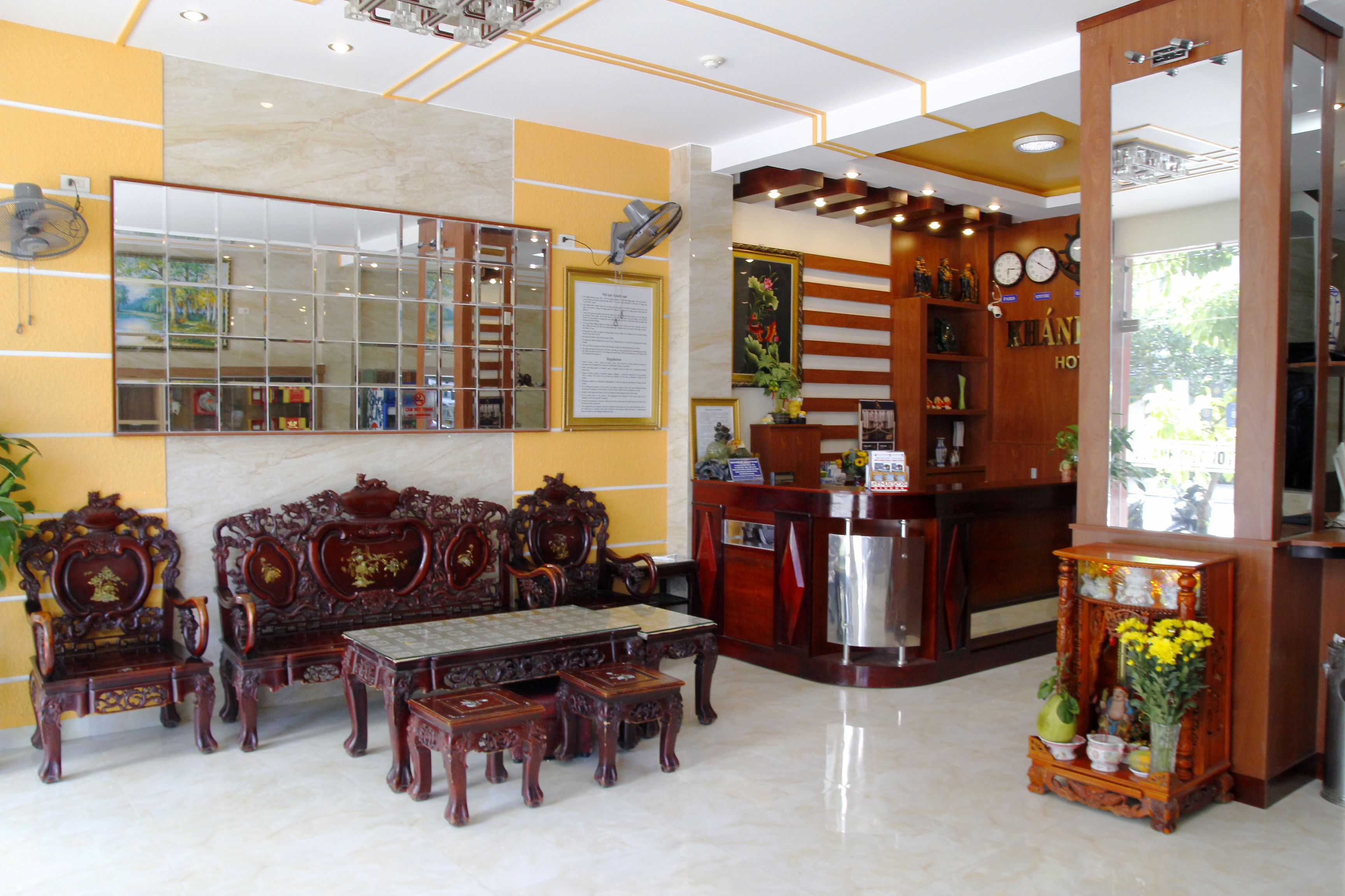 A lobby with a reception desk, a sofa set, and a mirror.