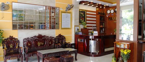 A lobby with a reception desk, a sofa set, and a mirror.