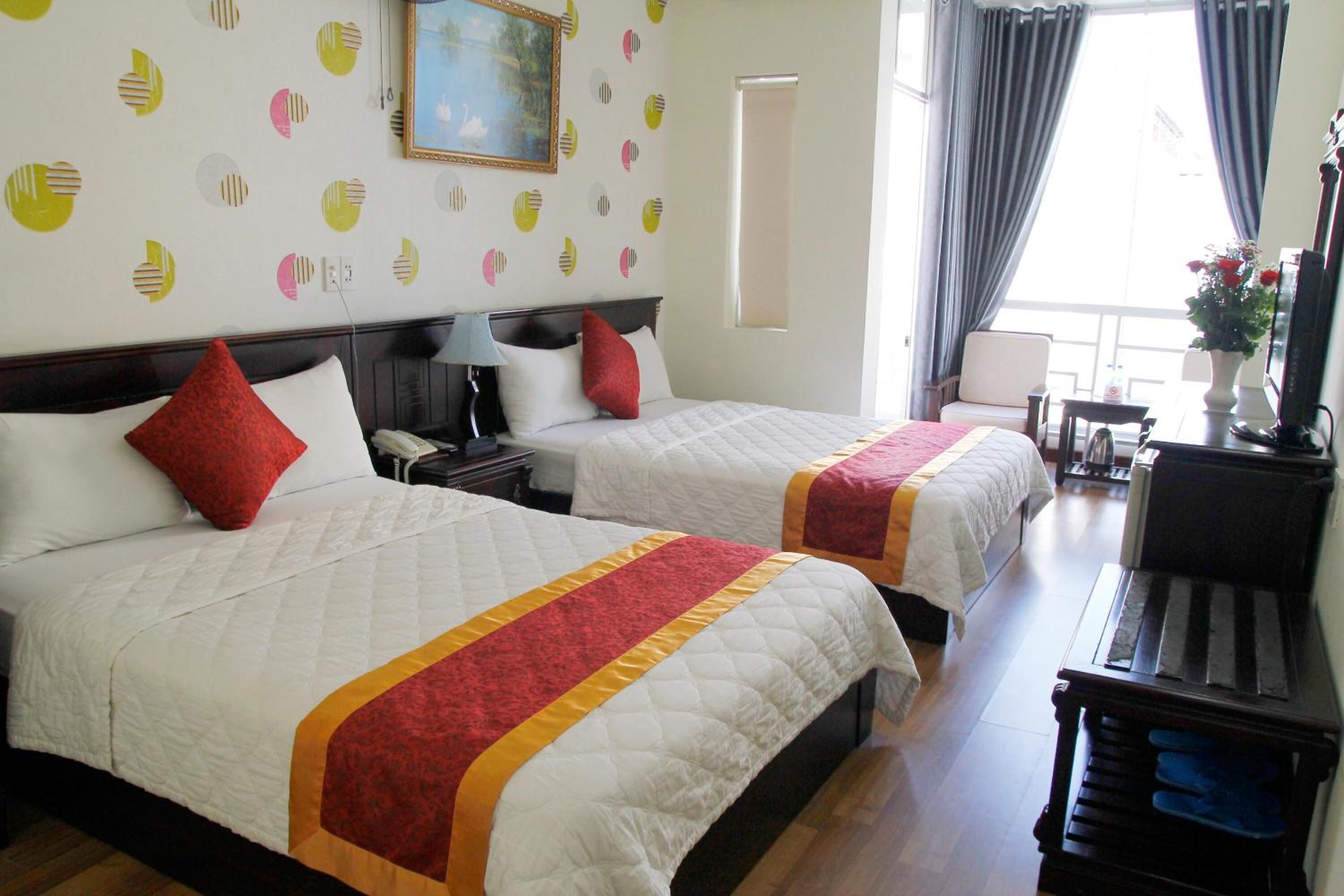 A hotel room with two beds, a desk, a chair, and a piano.