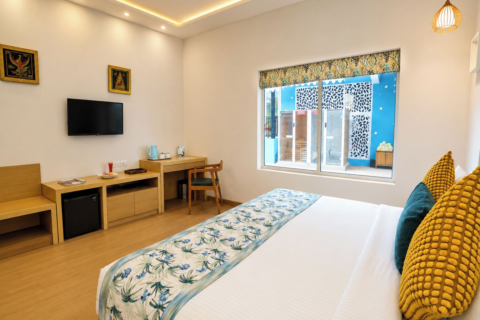 Ein Hotelzimmer mit Bett, Schreibtisch, Sessel, Fernseher und Fenster mit Außenblick.