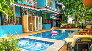 A hotel pool area with a hot tub, lounge chairs, and a decorative flamingo float. - The BeachWalk Resort by Acron (Candolim)