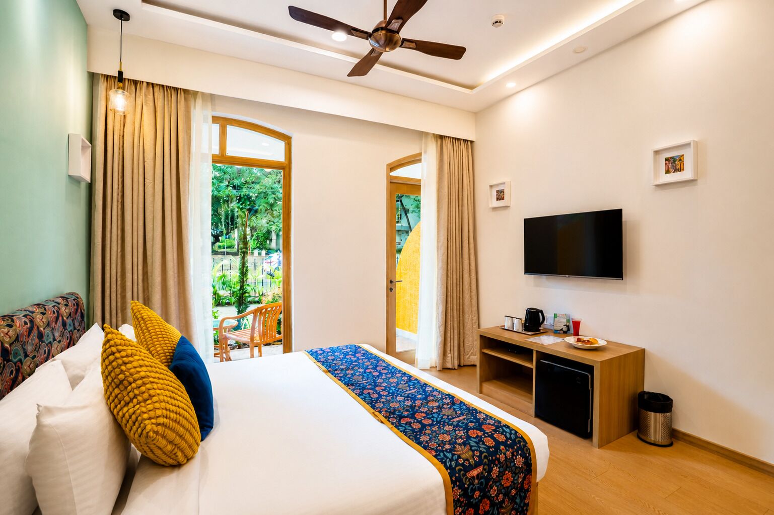 Une chambre d’hôtel équipée d’un lit, d’une télévision, d’un bureau et offrant une vue sur l’extérieur.