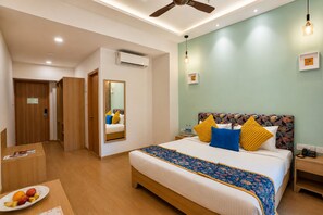 A hotel room with a bed, bedside table, and a mirror. - The BeachWalk Resort by Acron (Candolim)