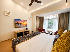 A hotel room with a bed, a desk, a chair, a television, and a window with curtains. - The BeachWalk Resort by Acron (Candolim)
