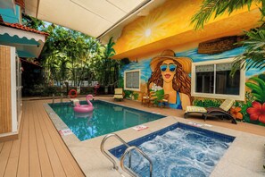 Une piscine intérieure agrémentée d’une fresque murale, d’un jacuzzi et de chaises longues.