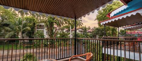 A balcony with a wooden ceiling, metal railing, and two wicker chairs.