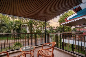 A balcony with a wooden ceiling, metal railing, and two wicker chairs. - The BeachWalk Resort by Acron (Candolim)