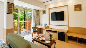 A modern living room with a sofa, dining table, and a TV mounted on the wall. - The BeachWalk Resort by Acron (Candolim)