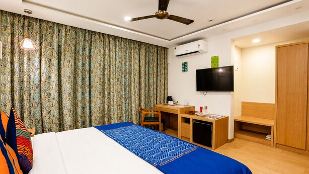 A hotel room with a bed, desk, chair, television, wardrobe, and an air conditioning unit. - The BeachWalk Resort by Acron (Candolim)