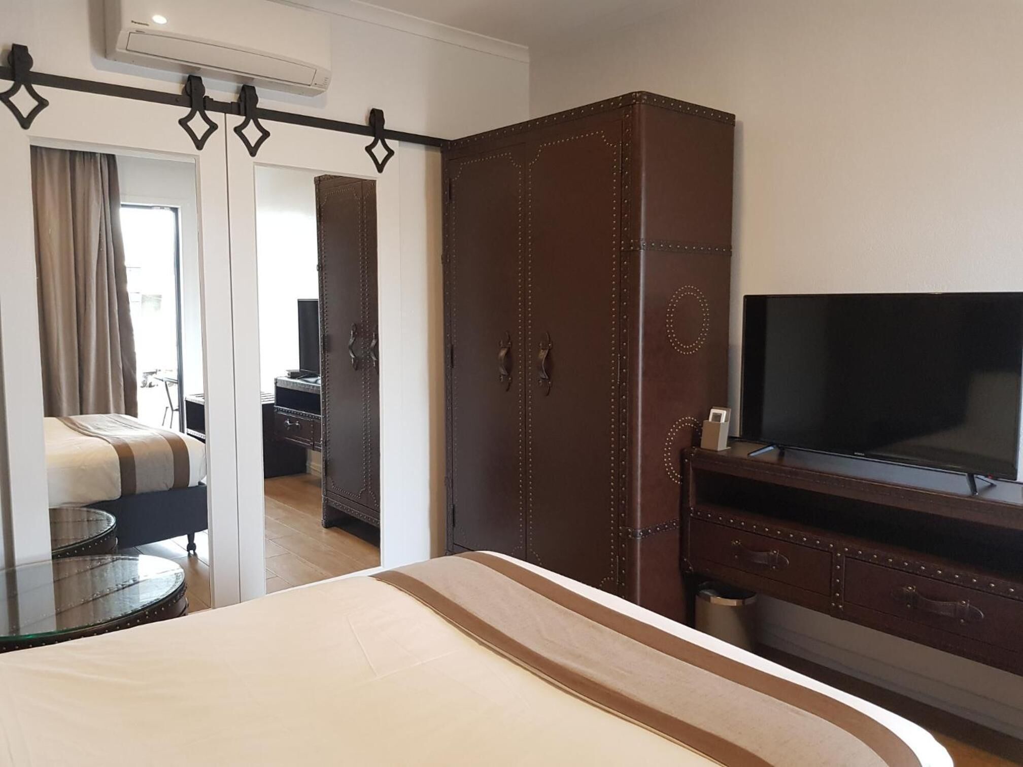 Een hotelkamer met een bed, een kledingkast, een televisie en een bureau.