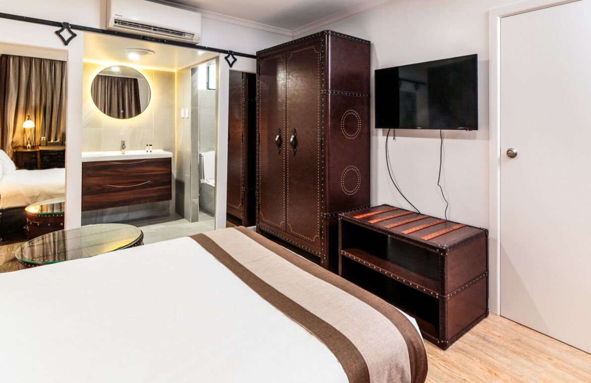 A hotel room with a large bed, a wardrobe, a television, and a small table.