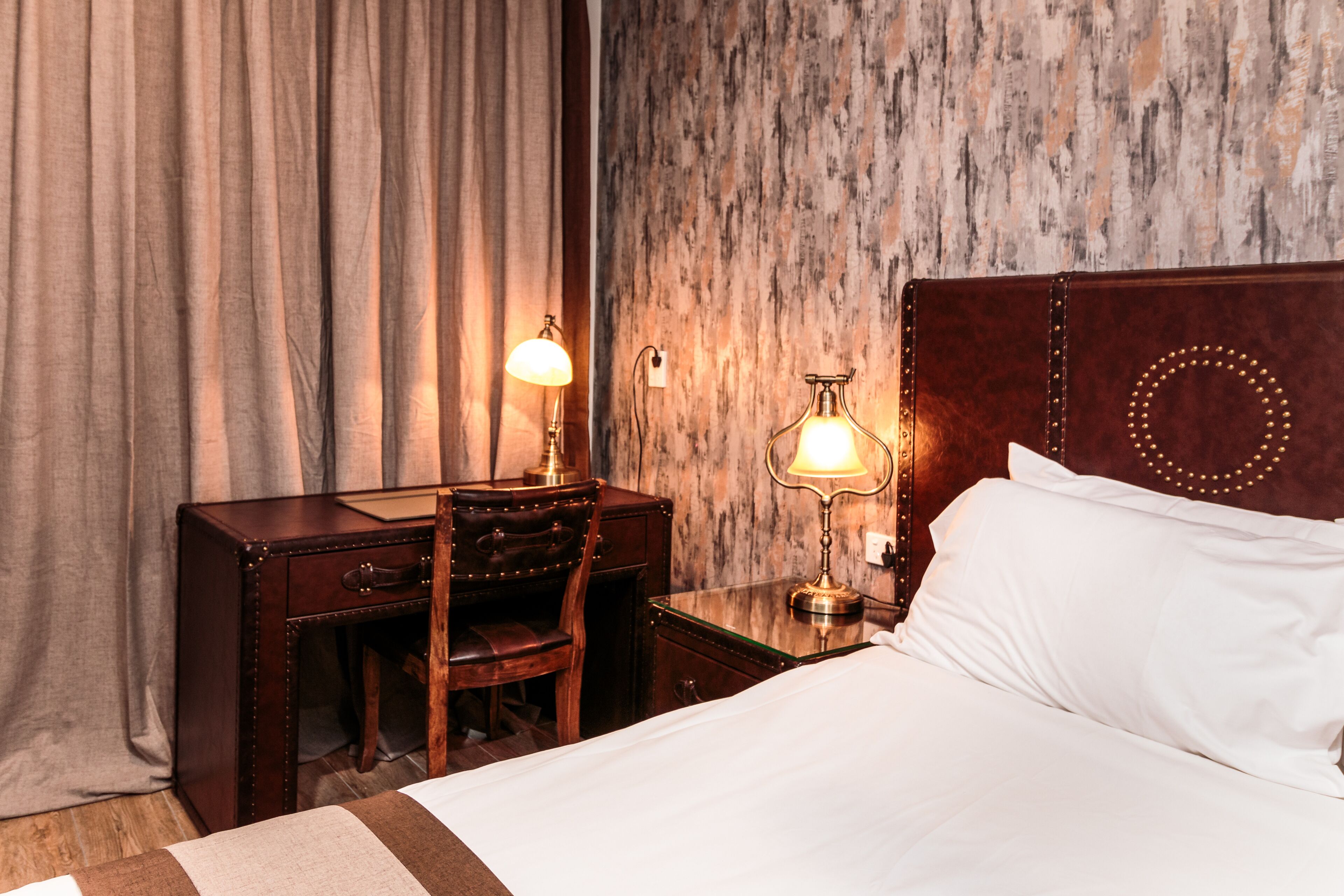 Een hotelkamer met een bed, een bureau met een stoel en twee lampen.