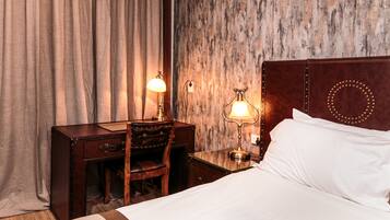 Een hotelkamer met een bed, een bureau met een stoel en twee lampen.