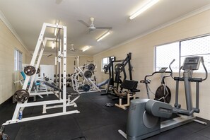 Un gimnasio con diversos equipos de ejercicio, incluyendo una banca de pesas, una cinta de correr y una bicicleta estática.