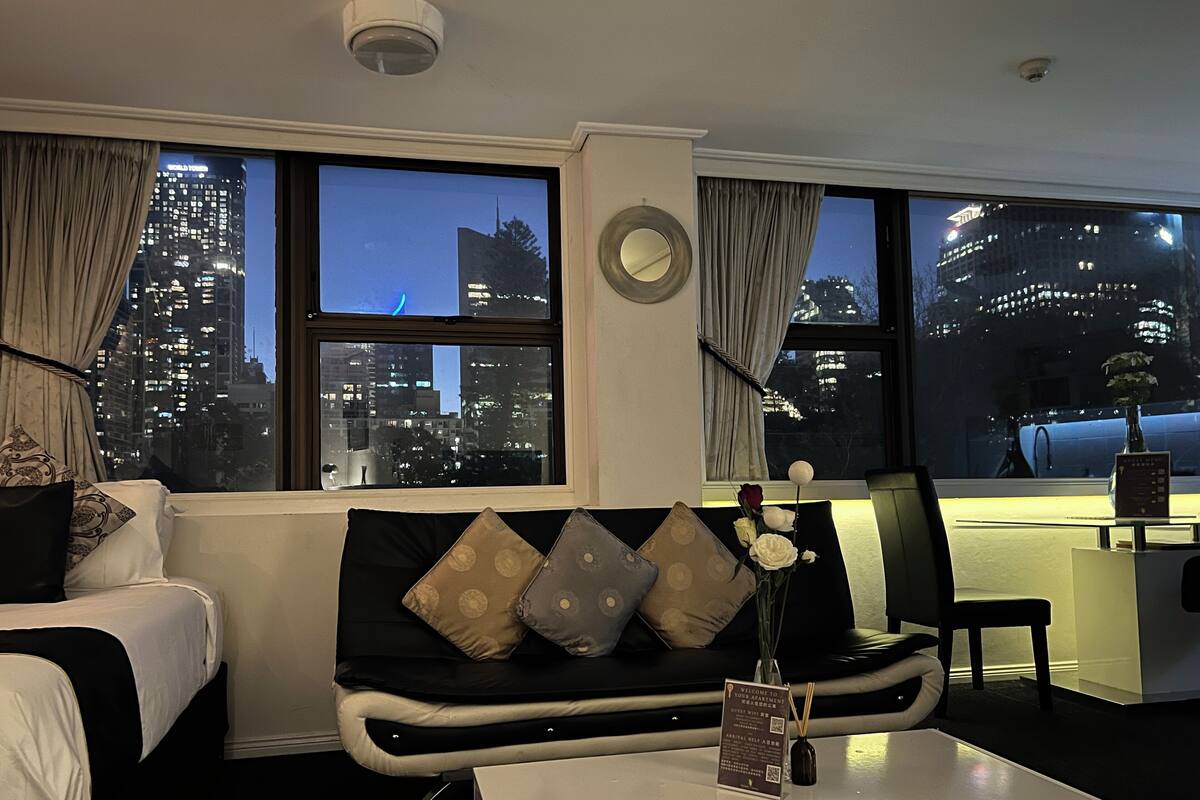 Habitación de hotel moderna con sofá, mesa de centro y vista a la ciudad iluminada por la noche.
