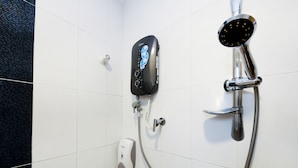 Una ducha con control manual, cabezal de ducha de mano y dispensador de jabón.