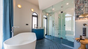 Un baño moderno con una bañera independiente, cabina de ducha de vidrio y un tocador con mueble azul.