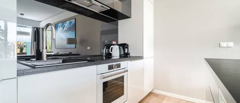 A modern kitchen with a built-in oven, a coffee maker, and a stainless steel sink.