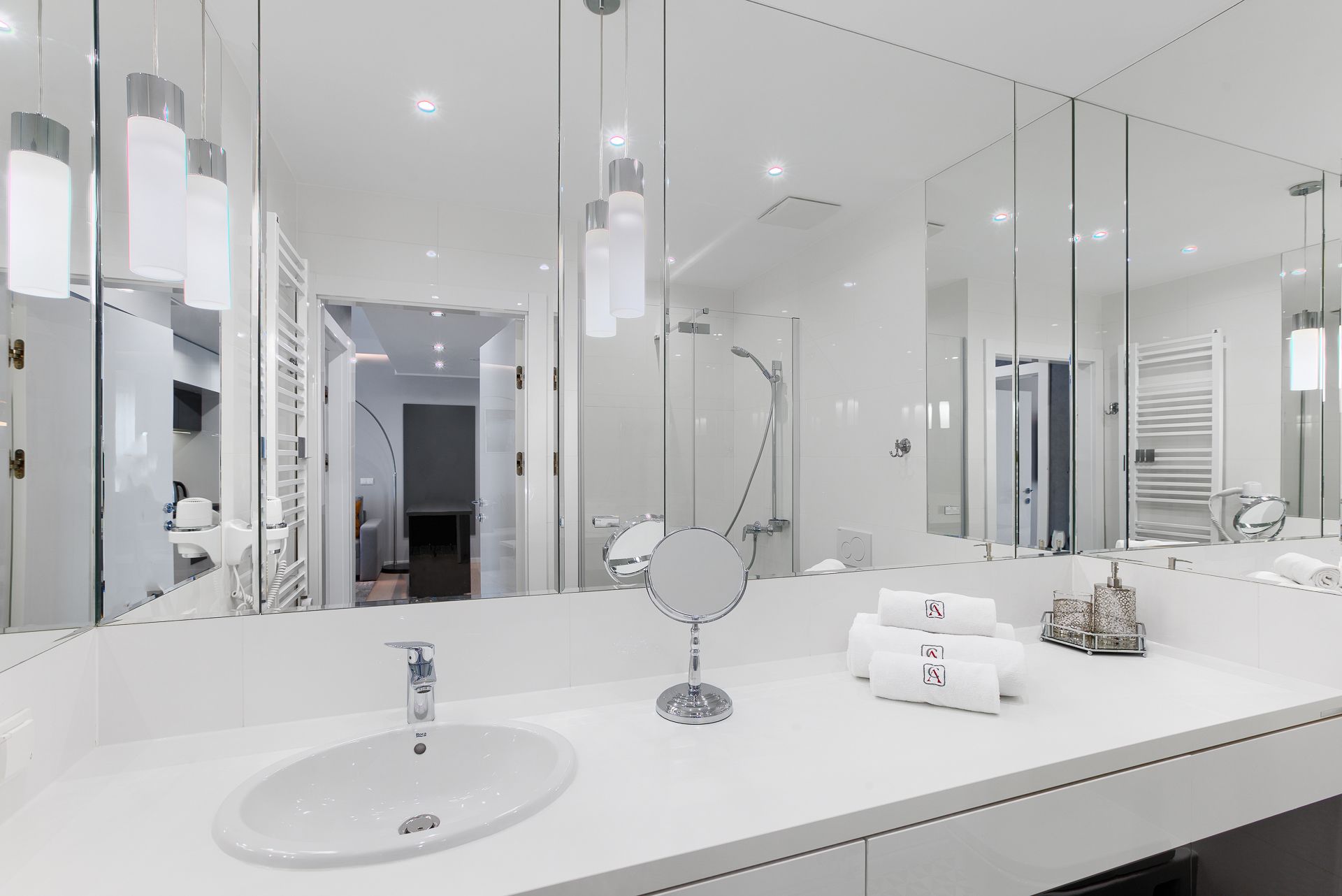 A modern bathroom with a large mirror, a sink, and a shower.