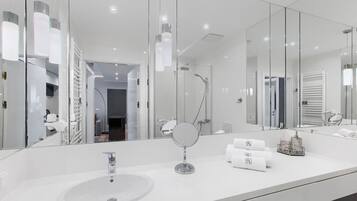 A modern bathroom with a large mirror, a sink, and a shower.