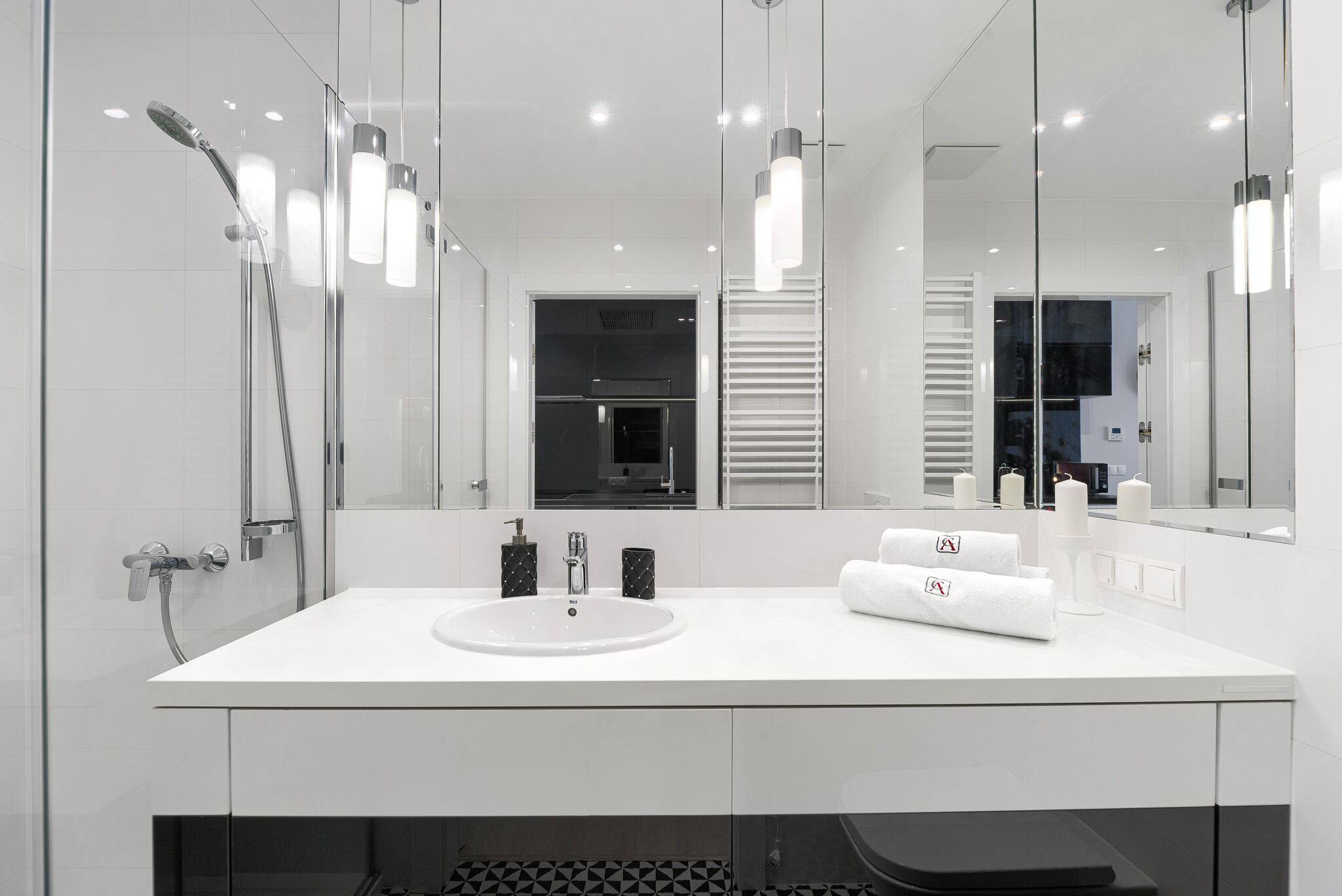 A modern bathroom with a white sink, a glass shower enclosure, and a large mirror.