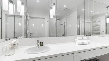 A modern bathroom with a large mirror, a white sink, and a glass shower enclosure.