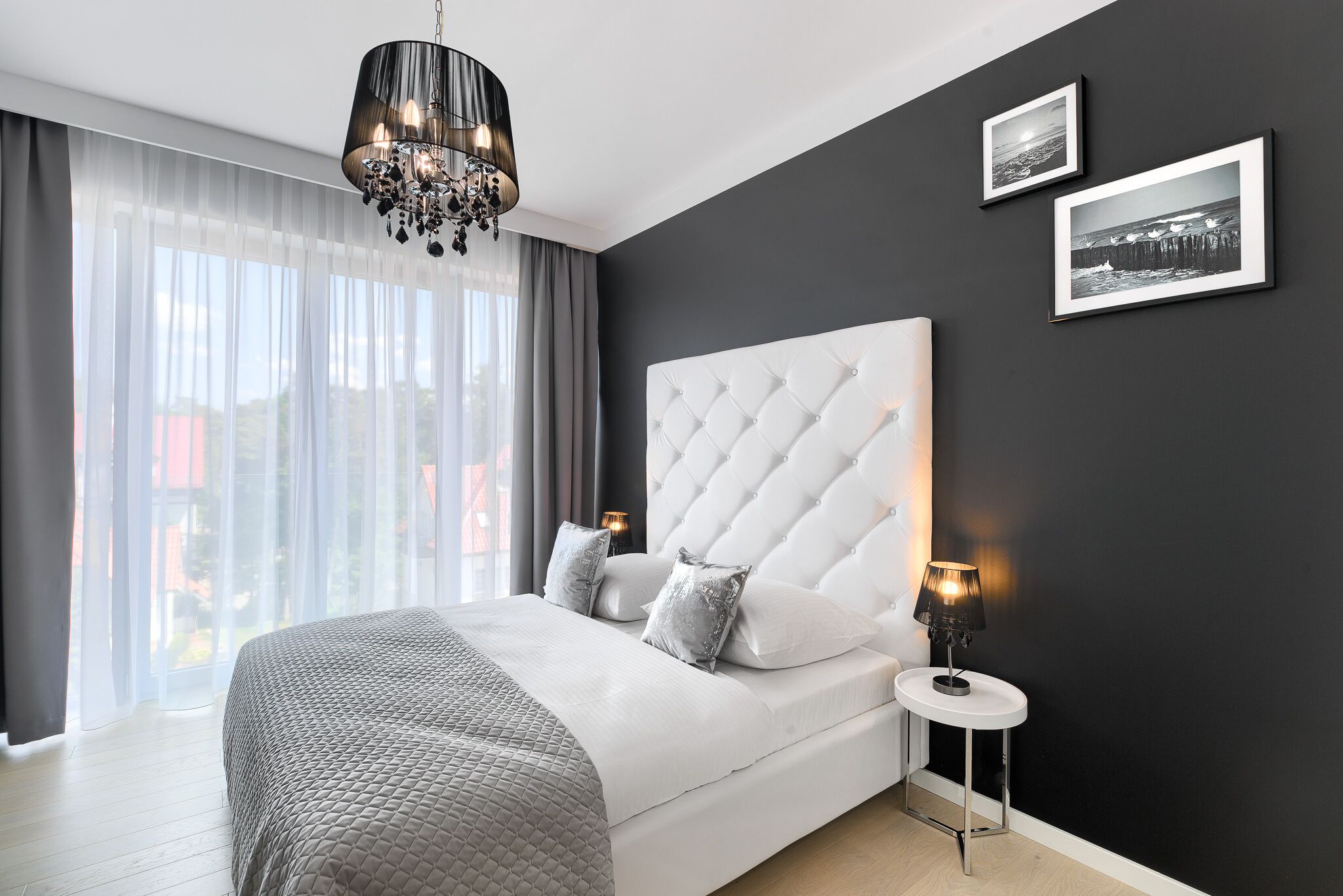 Un dormitorio moderno con una cama grande, una araña y dos cuadros en la pared.