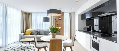 A modern kitchen with a round dining table, two chairs, and a pendant light.