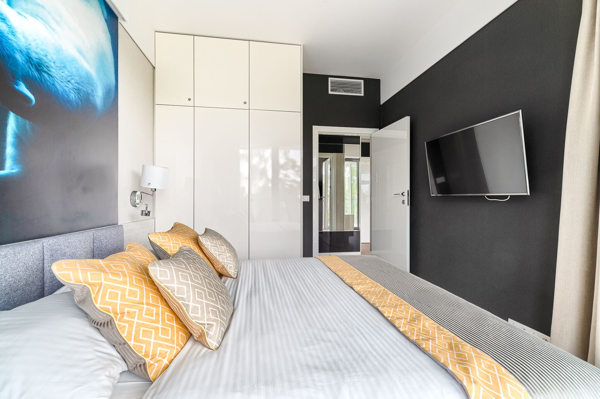A modern hotel room with a large bed, a flat-screen TV, and a painting on the wall.
