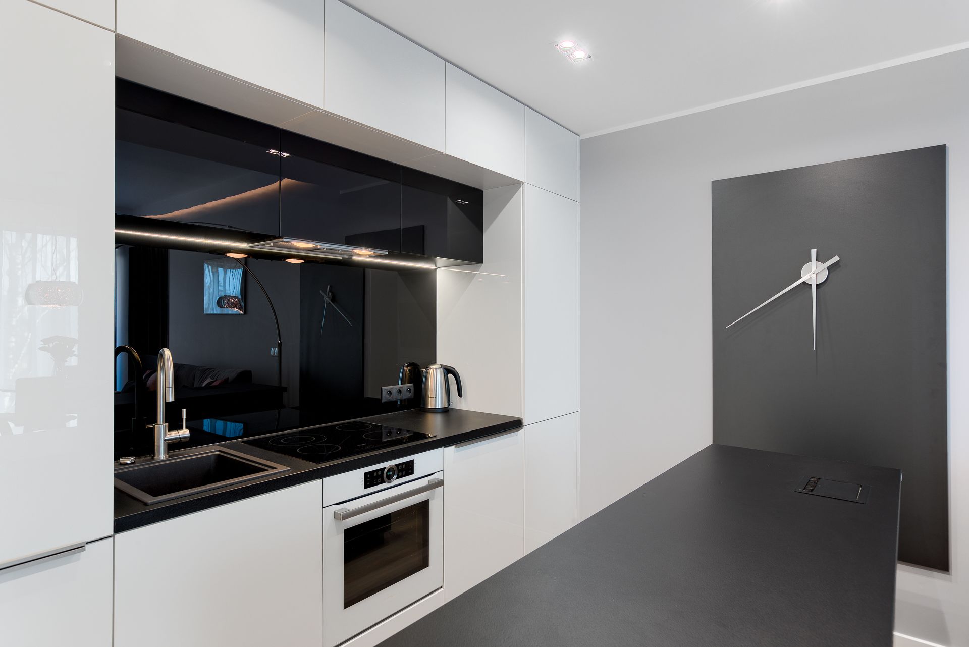 Una cocina moderna con encimera negra, electrodomésticos de acero inoxidable y un diseño minimalista.
