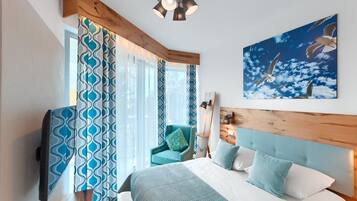 A bedroom with a bed, a chair, a TV, and a painting of birds.
