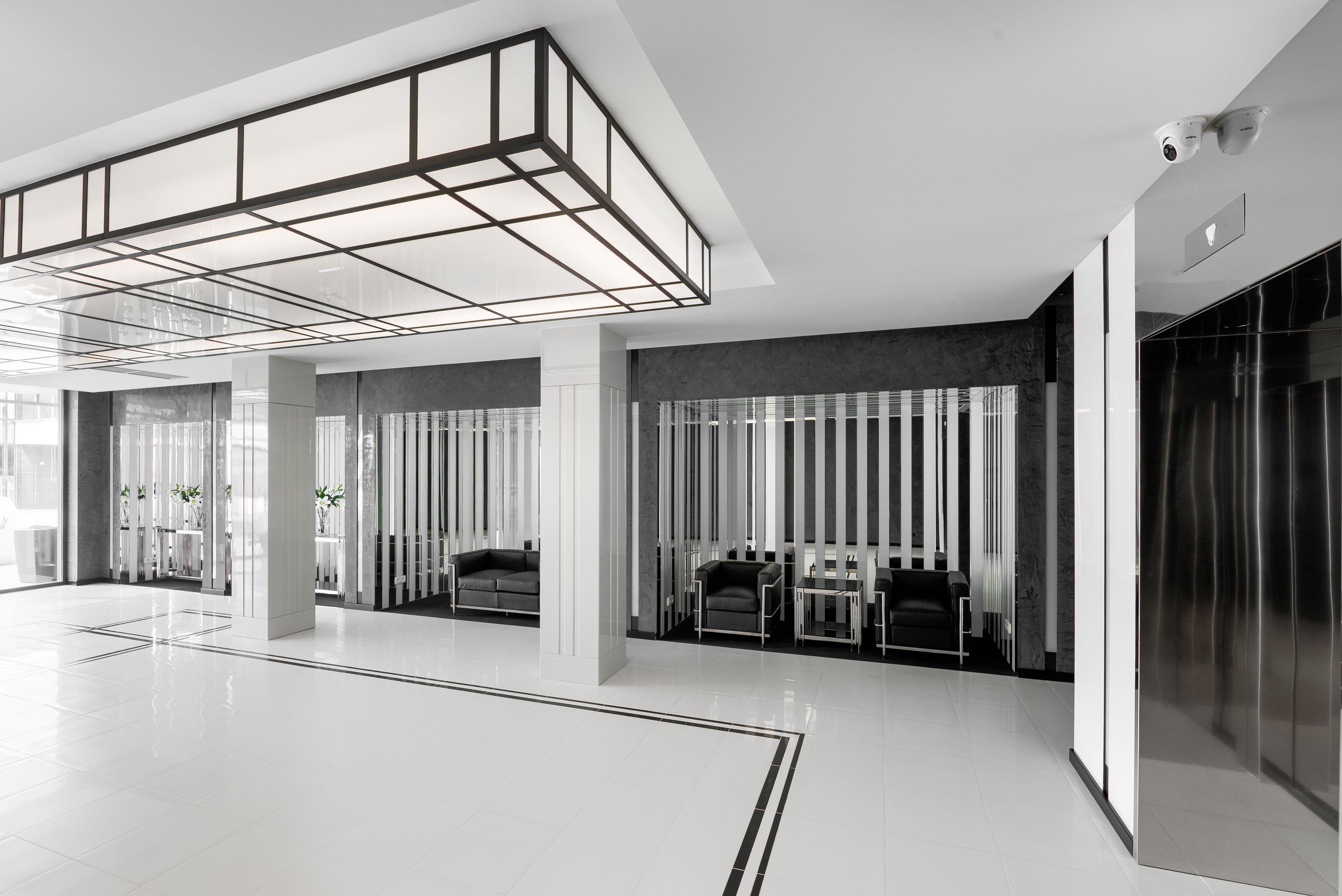 Een ruime lobby met een hoge plafond, moderne meubels en een strakke lift.