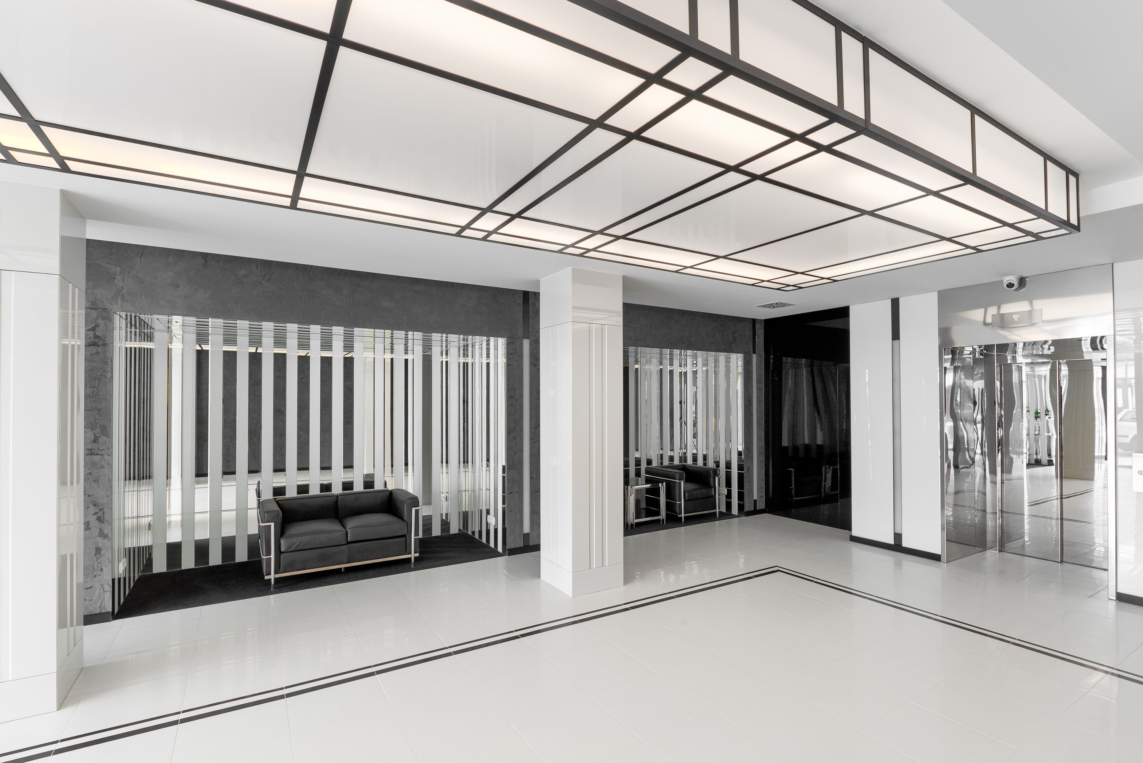 Een modern interieur met een modulaire bank, een glazen scheidingswand en een plafond met een rasterpatroon.