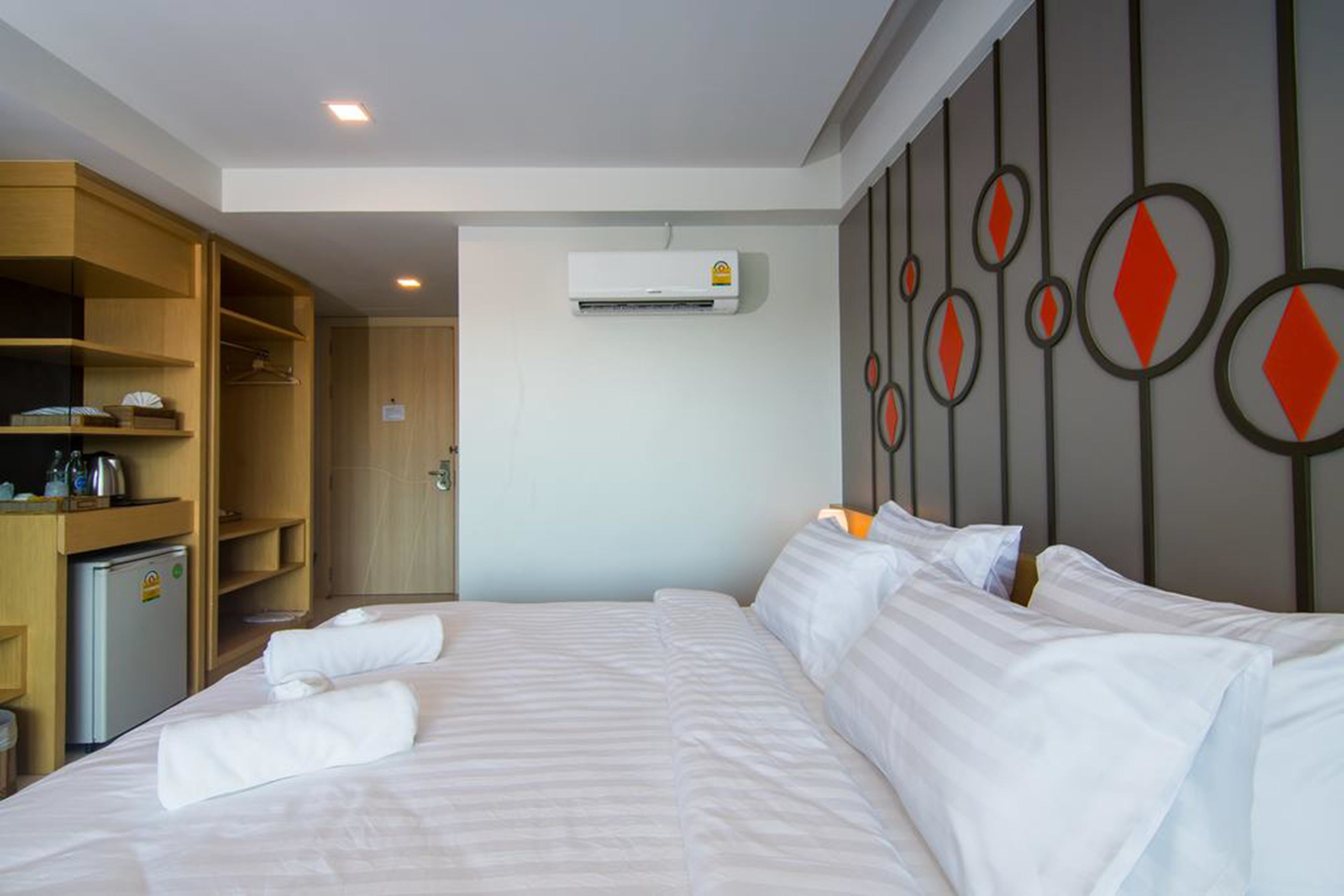A hotel room with a bed, a wardrobe, and an air conditioning unit.