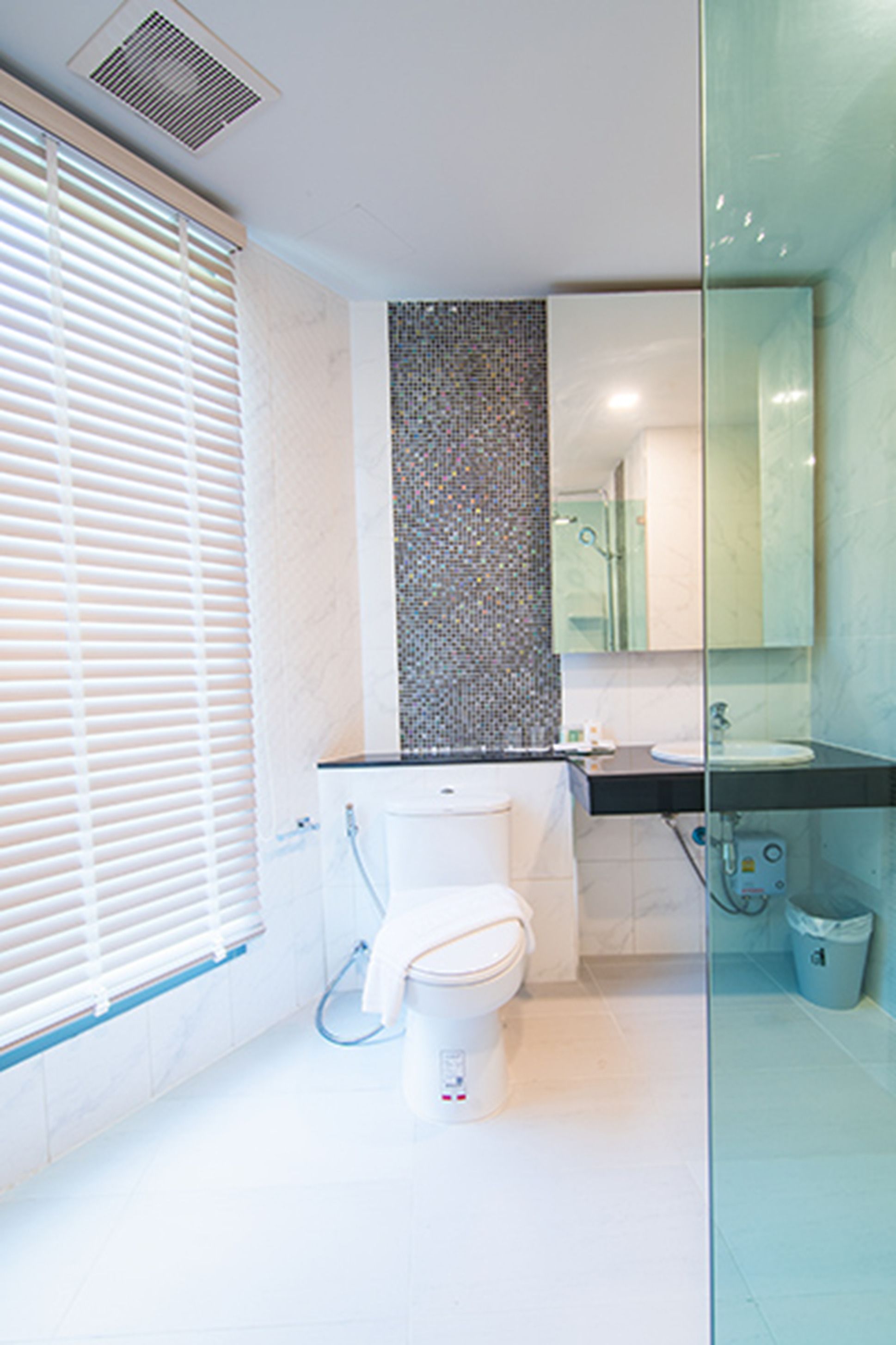 Ein modernes Badezimmer mit Toilette, Waschbecken und Duschkabine aus Glas.