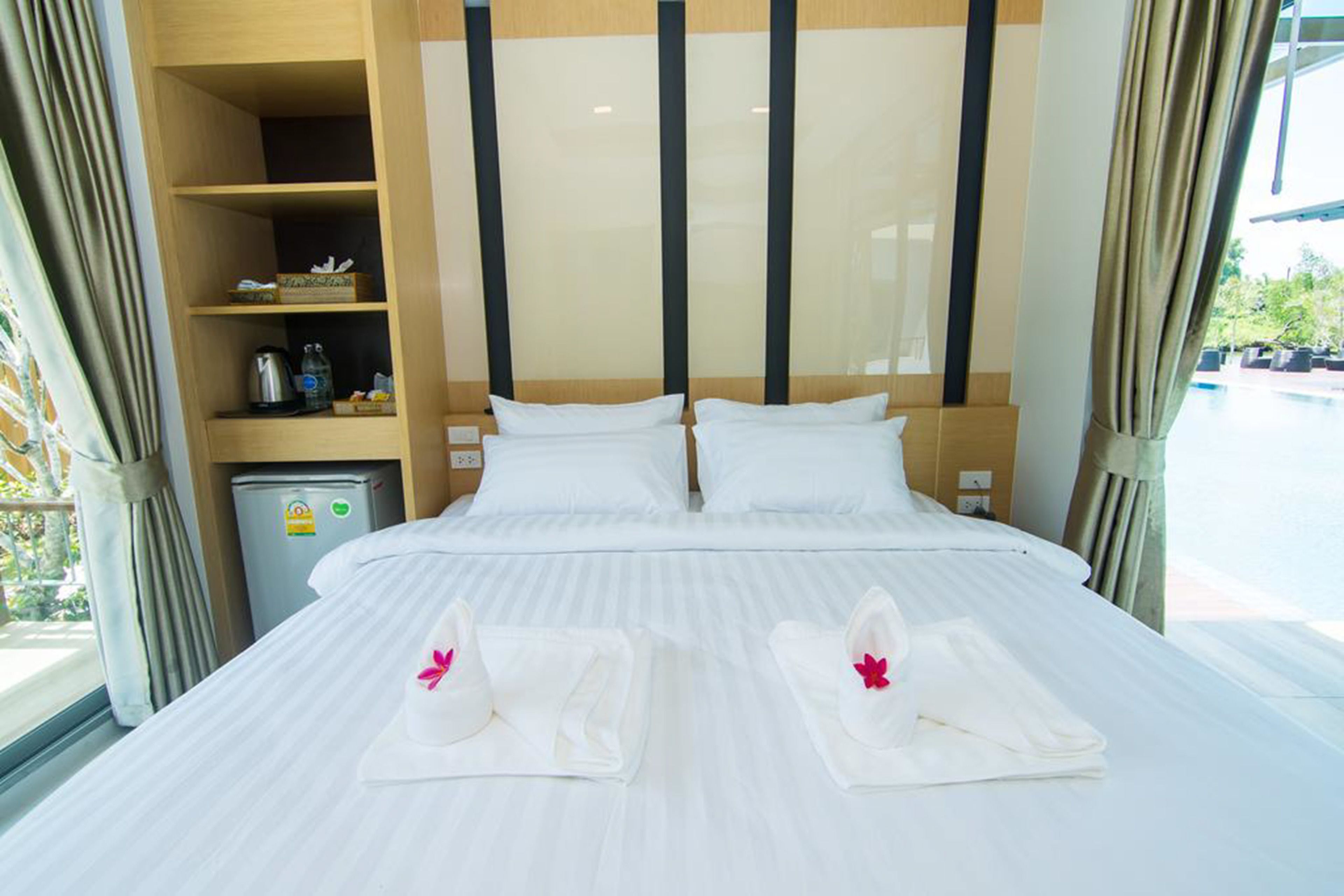 Habitación de hotel con una cama grande, dos almohadas, un minibar y vistas al exterior.