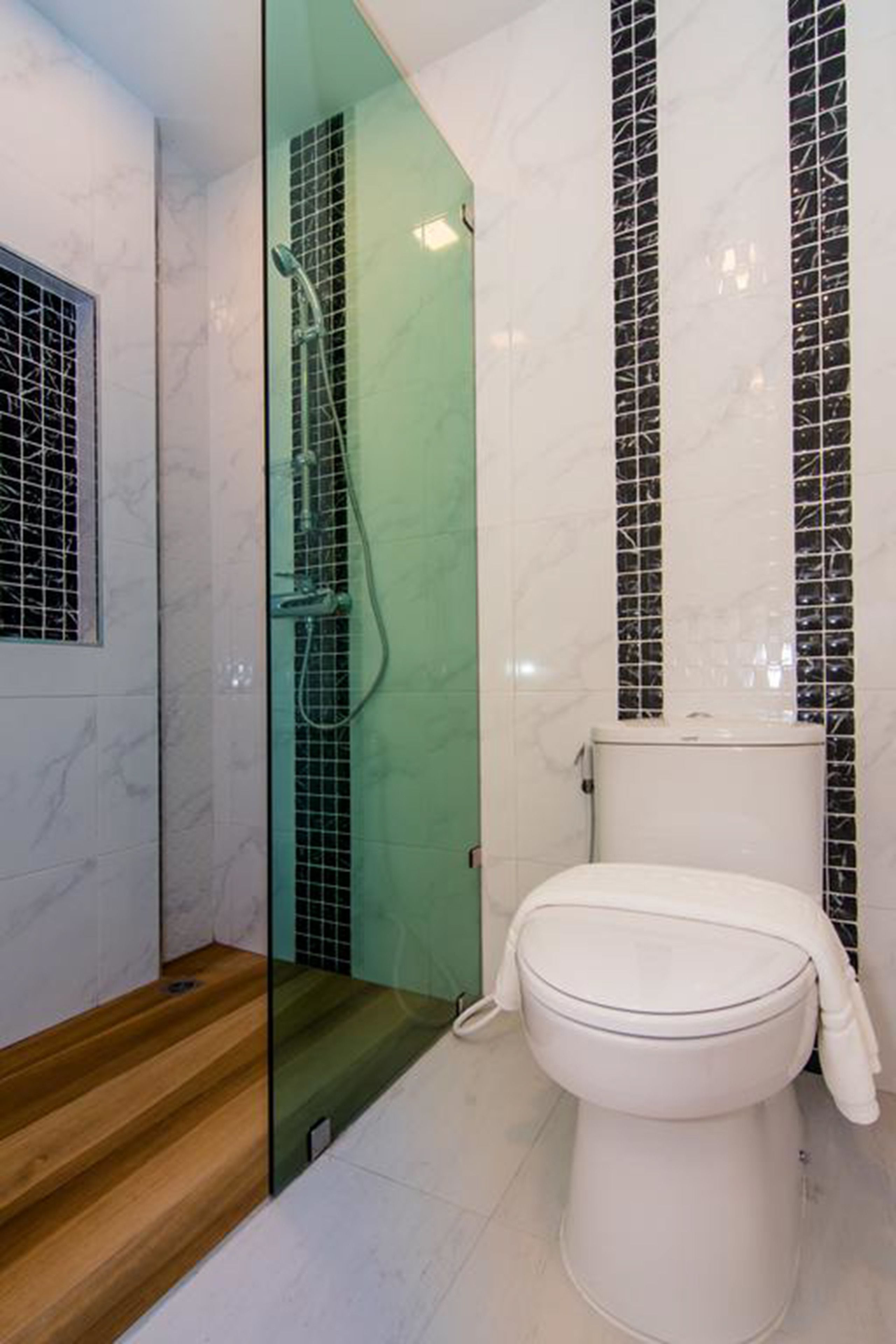 A modern bathroom with a glass-enclosed shower, a white toilet, and a marble-tiled wall.