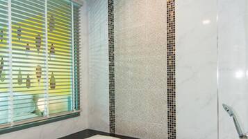 A modern bathroom with a large bathtub, a window with blinds, and a decorative tile backsplash.