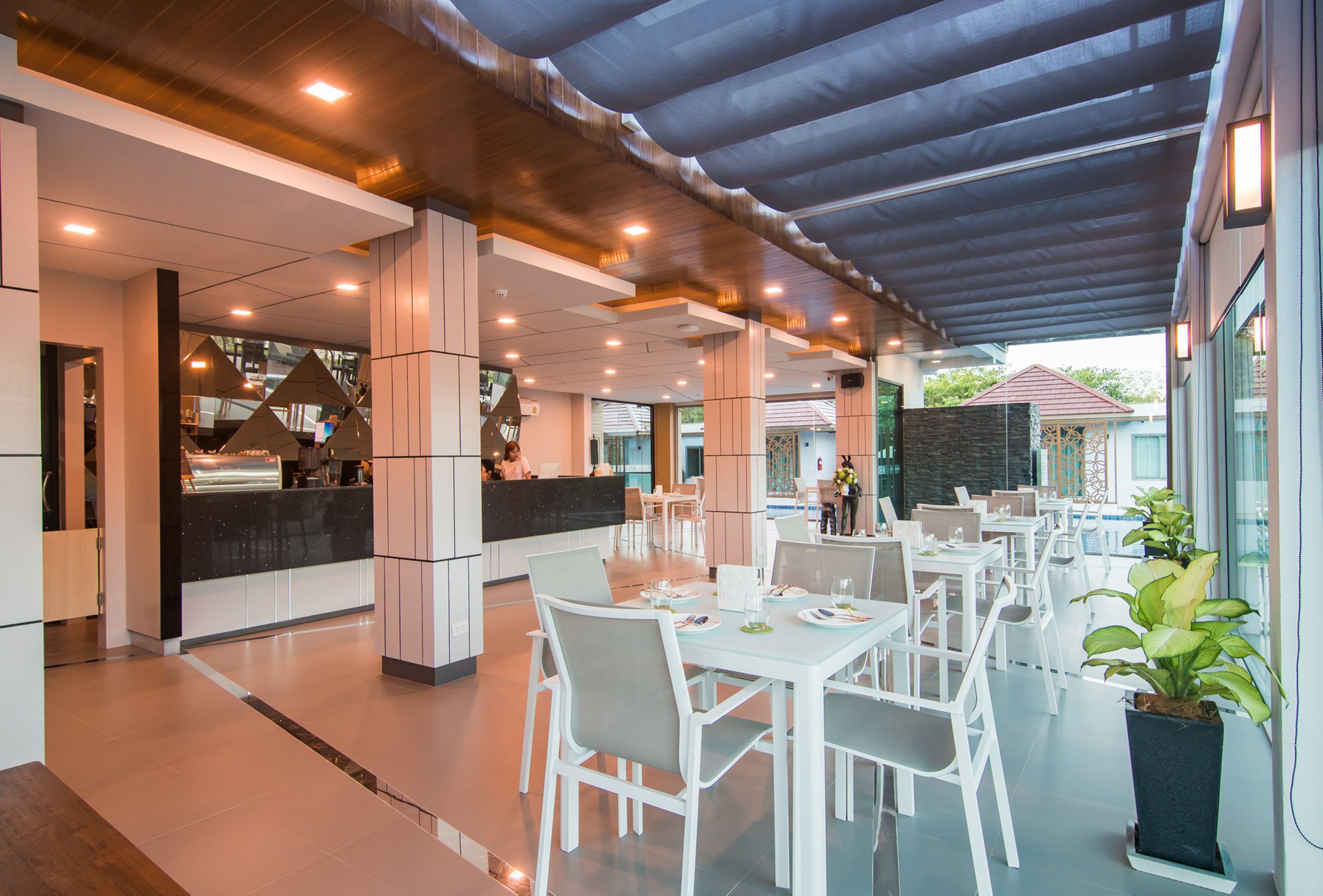 Een modern restaurant met witte meubels en een overdekt terras.