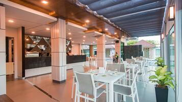 Een modern restaurant met witte meubels en een overdekt terras.