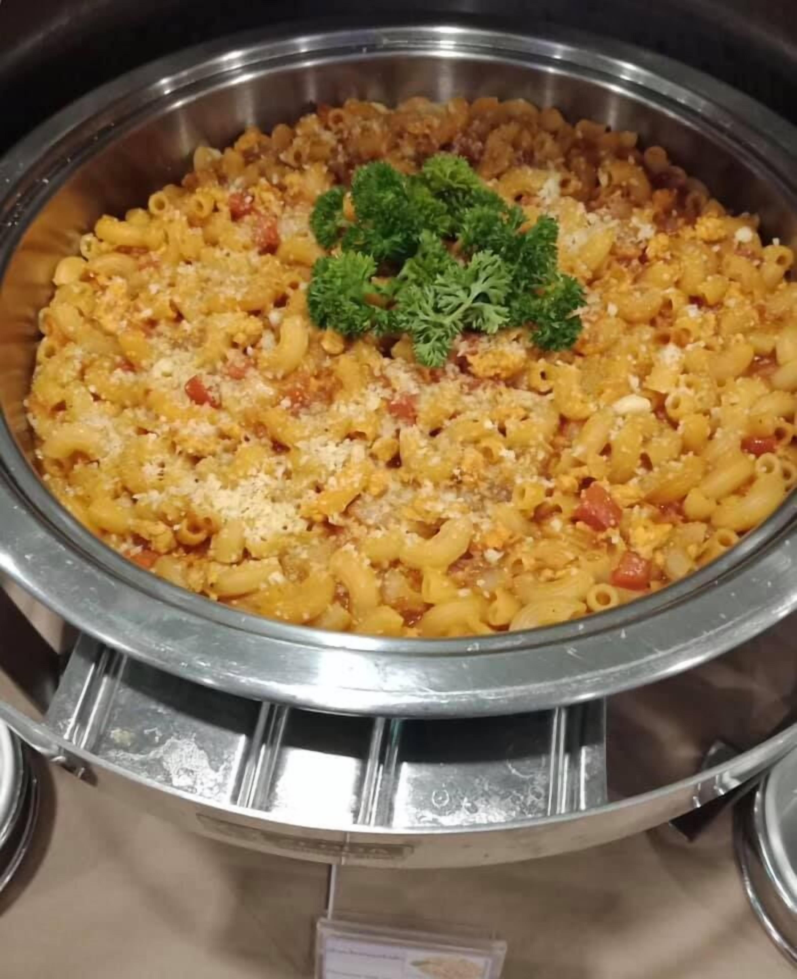 A buffet-style pasta dish with a garnish of parsley, served in a metal bowl.