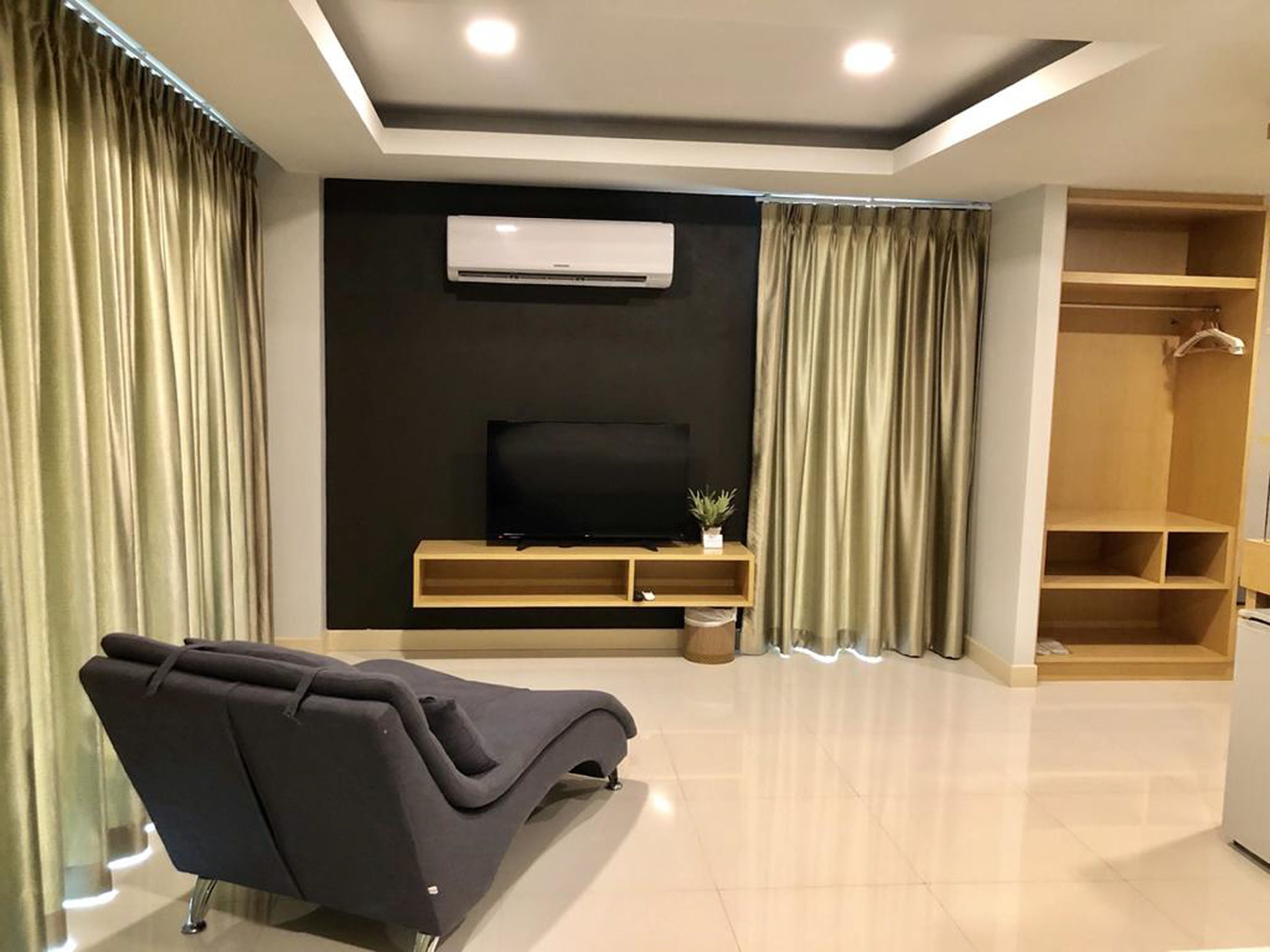 Una sala de estar moderna con un sofá, un televisor sobre un mueble de madera, aire acondicionado y un vestidor.