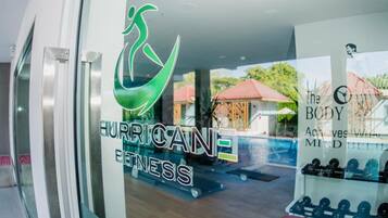 A gym with a logo that reads "HURRICANE FITNESS" and a sign that says "The BODY Achieves with MIND BELIEVING".