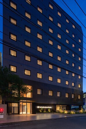 Un hôtel à plusieurs étages doté d’une façade moderne, avec des fenêtres régulièrement espacées et une entrée bien éclairée.