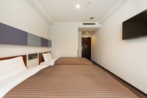 Une chambre d’hôtel dotée d’un grand lit, d’un téléviseur à écran plat fixé au mur et d’un panneau de commande situé sur la tête de lit.